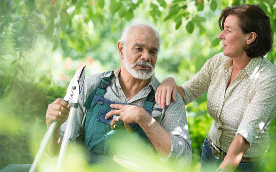 An elderly man working in the garden together with a mid-aged woman